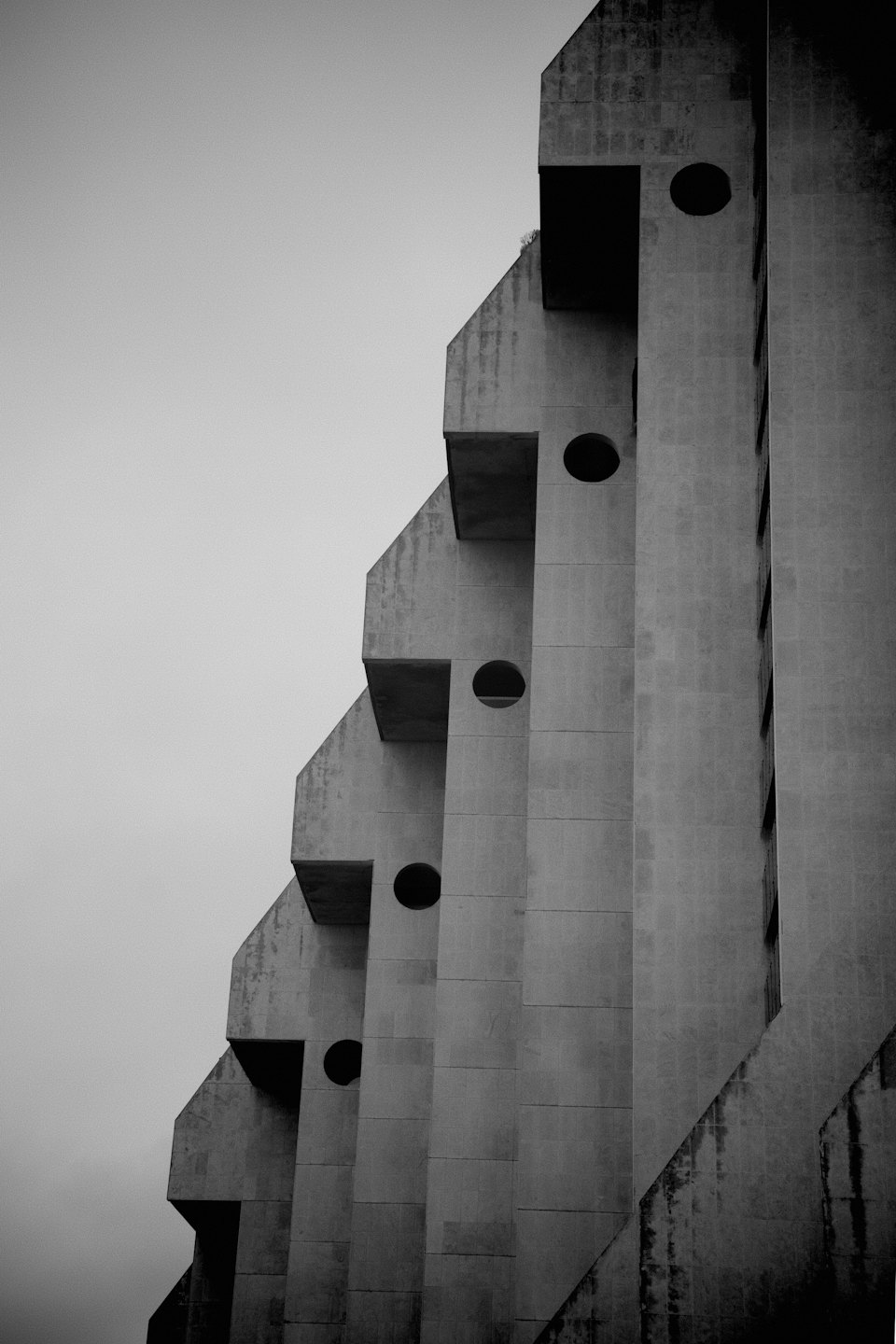 Geometric concrete facade of a brutalist building with circular windows.